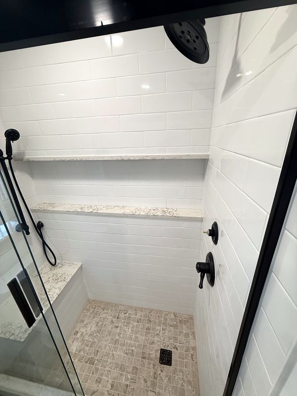 White tile shower with glass door and mosaic floor