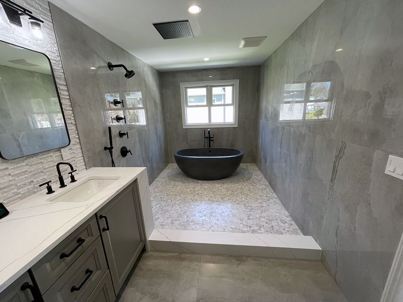 Primary bath with black freestanding tub and gray porcelain walls