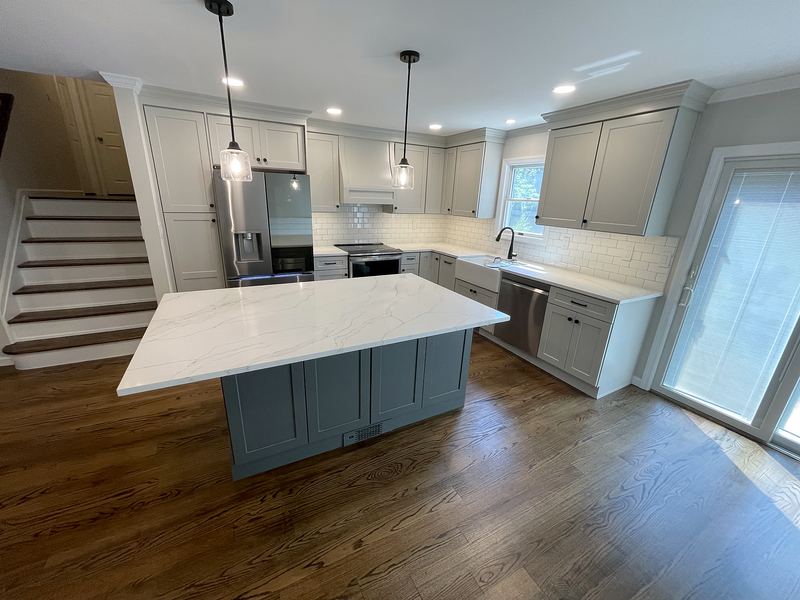 Open kitchen with gray island, white quartz top and pendant lights