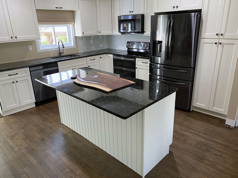 White kitchen with black granite island and beadboard panels