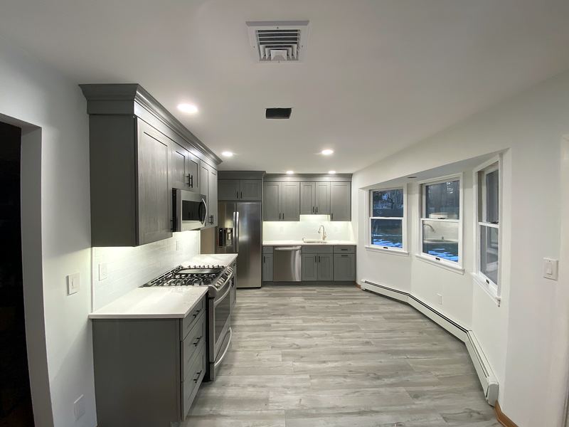 Gray shaker kitchen with bay windows and gray plank floors